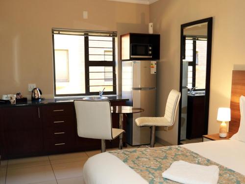 a room with a bed and a kitchen with a table and chairs at Eagle Nest Luxury Accommodation in Roodepoort