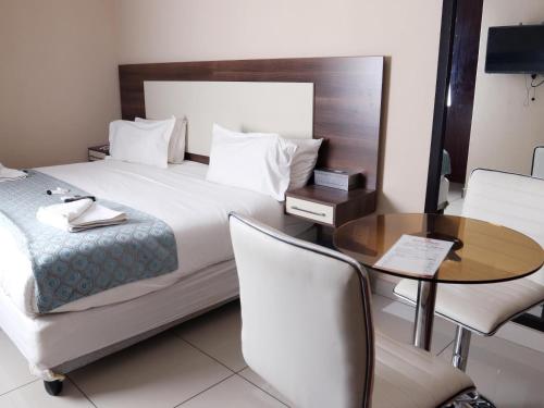 a hotel room with a bed and a table and chairs at Eagle Nest Luxury Accommodation in Roodepoort