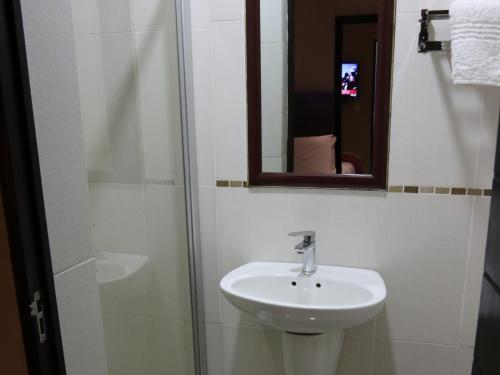 a bathroom with a sink and a shower with a mirror at Eagle Nest Luxury Accommodation in Roodepoort
