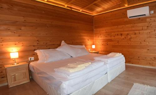 ein Schlafzimmer mit einem weißen Bett in einem Holzzimmer in der Unterkunft Villa Viridi in Sozopol