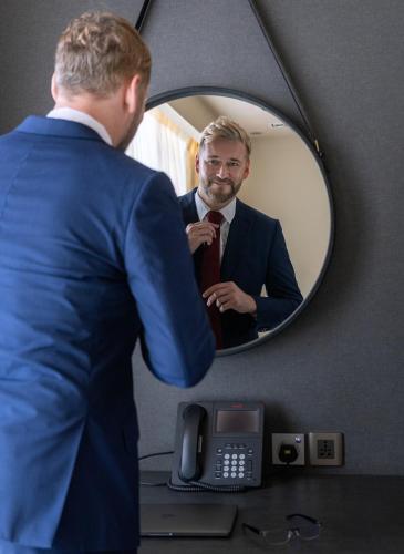 a man adjusting his tie in front of a mirror at The Art Hotel & Resort in Manama