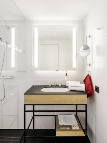 a white bathroom with a sink and a shower at IntercityHotel Zürich Airport in Rümlang