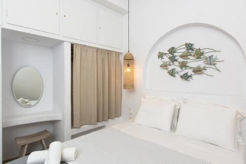 Un dormitorio blanco con una cama y un espejo. en Sea & City Naxos, en Naxos Chora