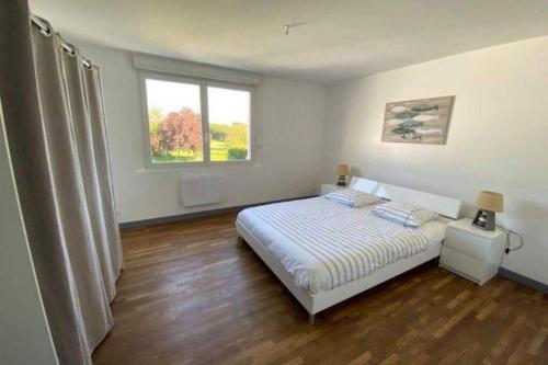 a white bedroom with a bed and two windows at Maison de 2 à 8 personnes 5 chambres in Portbail