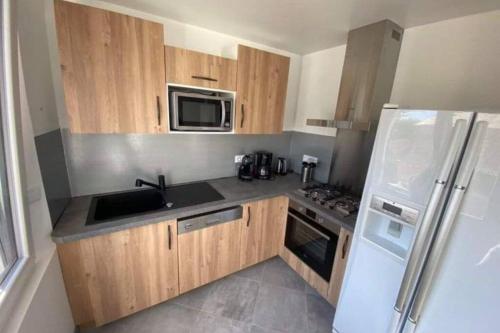 une cuisine avec des armoires en bois et un réfrigérateur blanc dans l'établissement Maison de 2 à 8 personnes 5 chambres, à Portbail