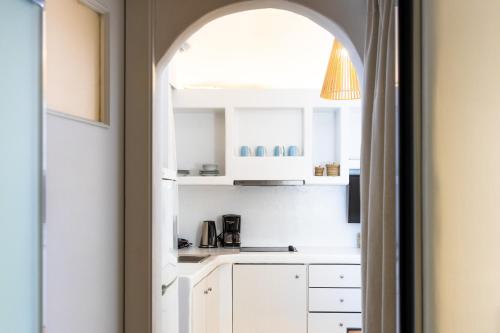 una cocina con armarios blancos y un arco en Sea & City Naxos, en Naxos Chora