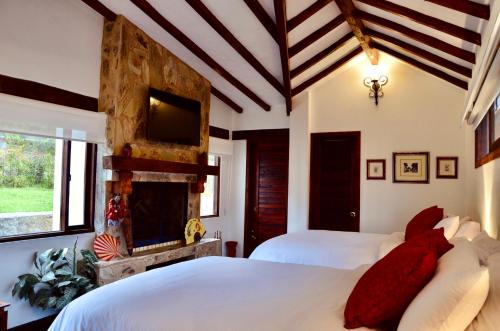 a bedroom with two beds with red pillows and a tv at Sumangá Hotel Boutique in Sutatausa