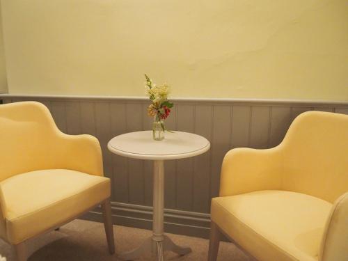 a table with a vase of flowers and two chairs at Houndgate Townhouse in Darlington