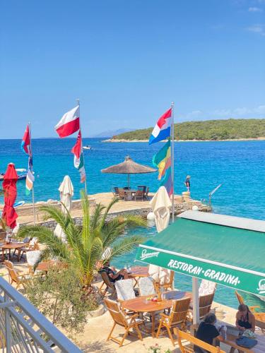 a beach with chairs and tables and flags on the beach at Guesthouse Gradina in Lovište