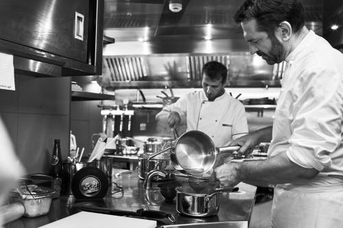 two men standing in a kitchen preparing food at Villa Bordeaux in Fira