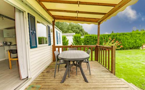 a patio with a table on a deck at Camping du Château Vert in Hondainville