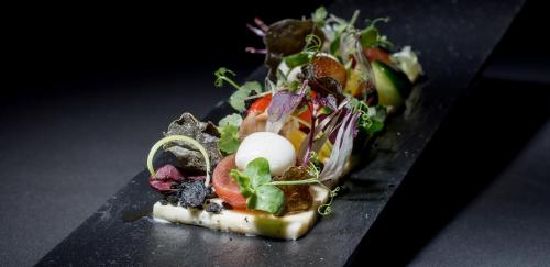 a piece of pizza with a salad on a black plate at Villa Bordeaux in Fira