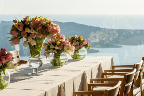 a long table with vases of flowers on it at Villa Bordeaux in Fira