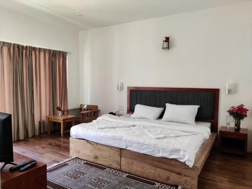 een slaapkamer met een groot bed en een televisie bij Rock Castle Residency in Leh