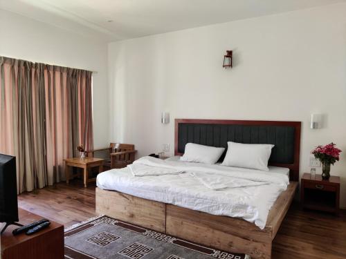 a bedroom with a large bed and a tv at Rock Castle Residency in Leh