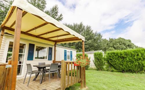 a patio with a table and chairs under a canopy at Camping du Château Vert in Hondainville