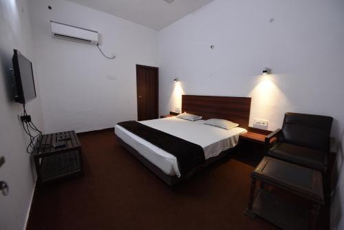 a hotel room with a bed and a chair at Hotel Mayur in Gorakhpur