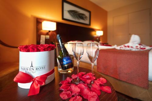a table with two wine glasses and red roses at Hotel de Berny in Antony