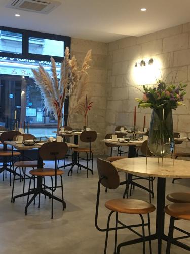 a restaurant with tables and chairs and flowers in a room at Hôtel L'Adresse in Tours