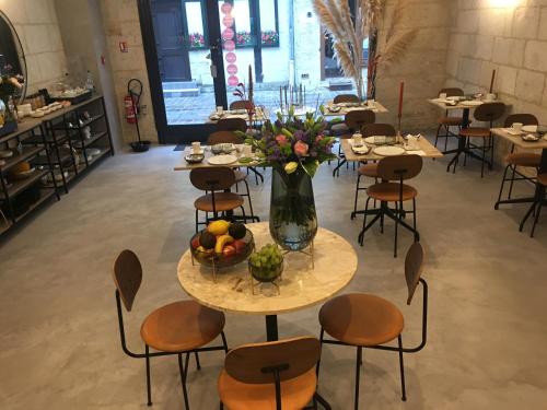 a room with tables and chairs and a vase of flowers at Hôtel L'Adresse in Tours