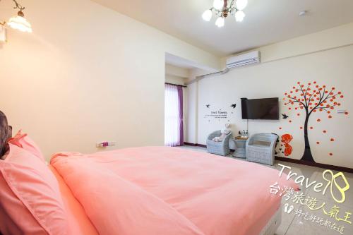 a bedroom with a pink bed and a flat screen tv at Hometown Times Homestay in Yuli