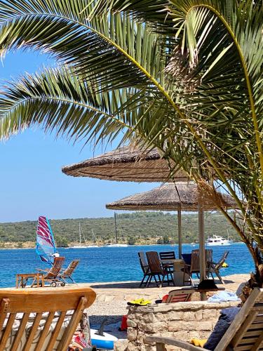 a beach with chairs and umbrellas next to the water at Guesthouse Gradina in Lovište