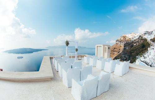 a view of the ocean from a rooftop with white chairs at Villa Bordeaux in Fira