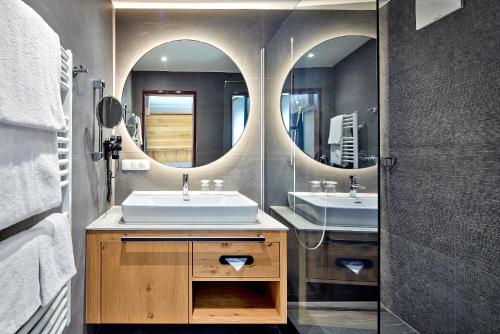 a bathroom with two sinks and a mirror at Fish'Inn Zell - Hotel Fischerwirt in Zell am See