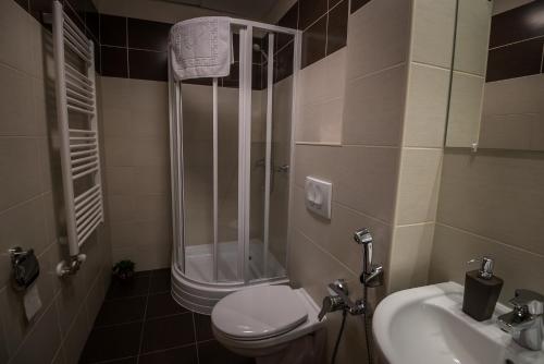 a bathroom with a shower and a toilet and a sink at Mokka Apartman Szeged in Szeged