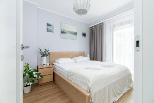 een slaapkamer met een bed met witte lakens en een raam bij Apartments Cracow Wawrzyńca by Renters in Krakau
