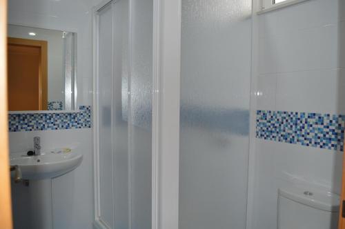 a white bathroom with a shower and a sink at Hotel Las Terrazas in Tazones