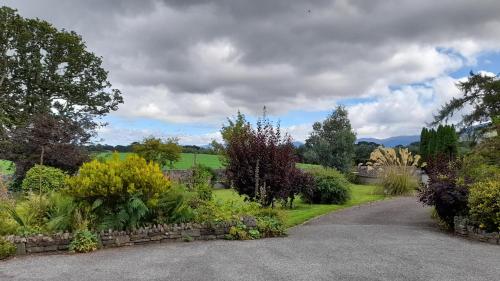 a garden with a stone wall and a driveway at Inveraray Farm in Beaufort