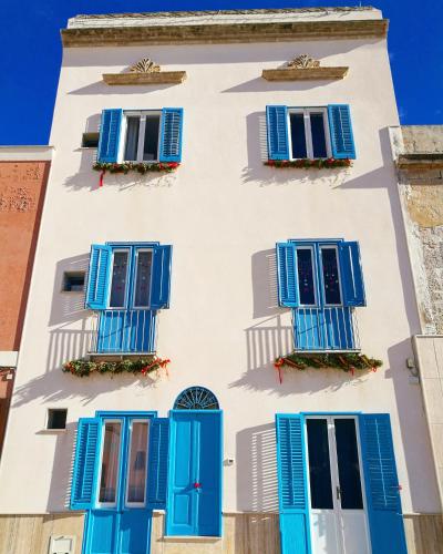 a building with blue shutters and windows at Casa Blue Windows pt in Favignana