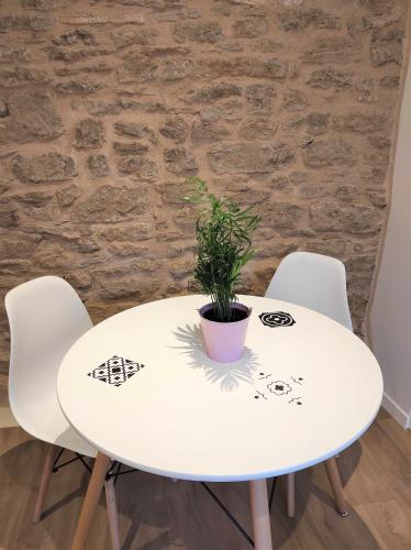 d'une table blanche et de deux chaises avec une plante. dans l'établissement Appartement Cogny - les Meublés des Pierres Dorées, à Theizé