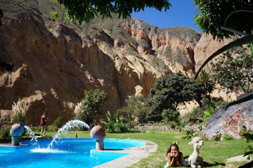 a woman sitting in front of a swimming pool in a mountain at Paraiso Las Palmeras Lodge in Cabanaconde