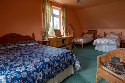 a bedroom with two beds and a desk and a window at Ferryview B&B in Cahersiveen