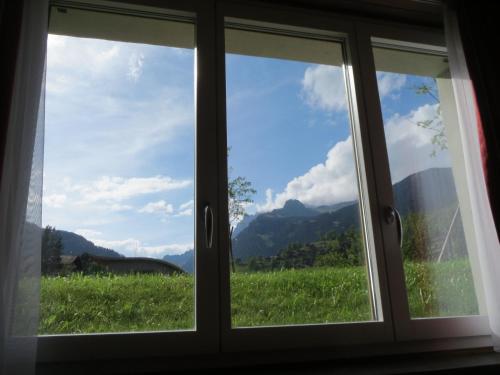 a window with a view of a field and mountains at MOM - Alpine Boutique Apartments, Romantica, near Grindelwald Terminal in Grindelwald