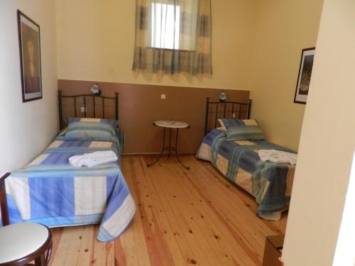 a room with two beds and a table in it at En Ermoupoli in Ermoupoli