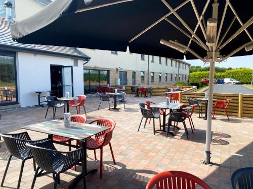 a patio with tables and chairs under an umbrella at The Gailes Hotel & Spa in Irvine