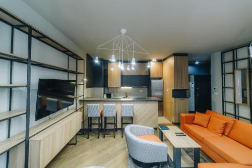 a living room with an orange couch and a kitchen at LUST PREMIUM Apartments in Kragujevac