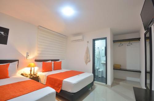 a hotel room with two beds and a bathroom at La Pera Hotel in Bucaramanga