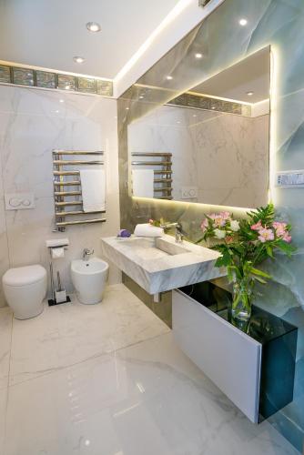 a bathroom with a sink and a toilet and a mirror at Luxury Beachfront Apartment Taormina Pool and Parking in Taormina