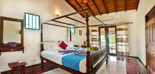 a bedroom with a canopy bed and a mirror at Garland Beach Villa in Ambalangoda
