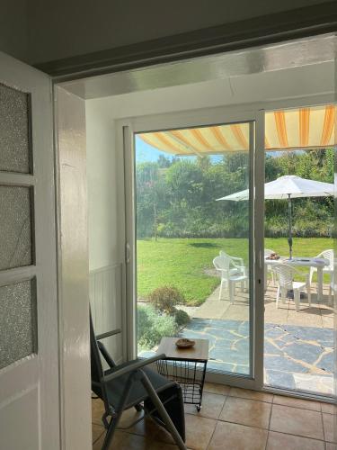 une porte coulissante en verre menant à une terrasse avec une chaise. dans l'établissement Les roses de l'Olivier, à Les Rosiers