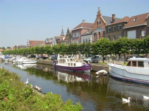 een groep boten aangemeerd in een rivier met huizen bij Hotel & Appartementen Royal in Sas van Gent