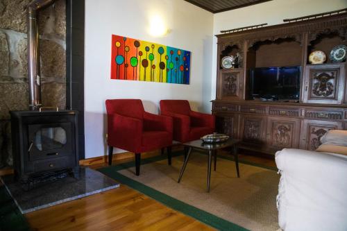 a living room with red chairs and a fireplace at Recanto da Avó in Seia