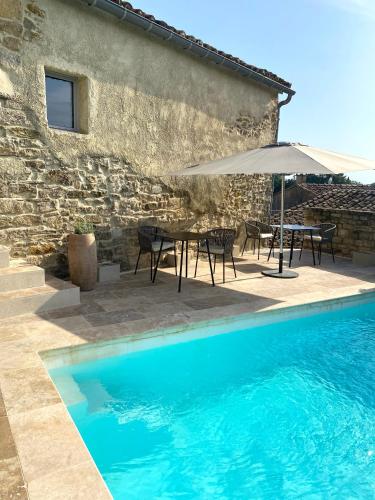 a villa with a swimming pool and a table and umbrella at La Maison des Vendangeurs - TABLE D'HÔTES le soir du jeudi au dimanche- Jacuzzi - Balnéo SPA - ACCES PISCINE pour toutes les chambres sauf STUDIO COQUET- Piscine de mai à mi-octobre in Martignargues