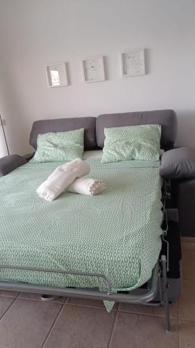 a hospital bed with green sheets and pillows at queen’s paradise in Callao Salvaje
