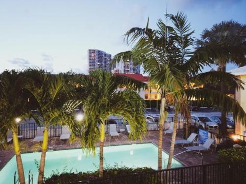 a pool with palm trees in a parking lot at The Beach House at Seascape Steps from the Beach, Marina and Shops! in West Palm Beach