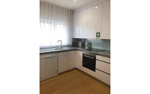 a kitchen with white cabinets and a sink at Casa do Meio in Paredes